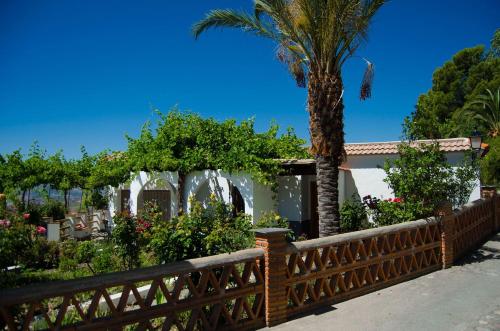 a wooden fence with a palm tree and flowers at Casa Número 1 in Válor