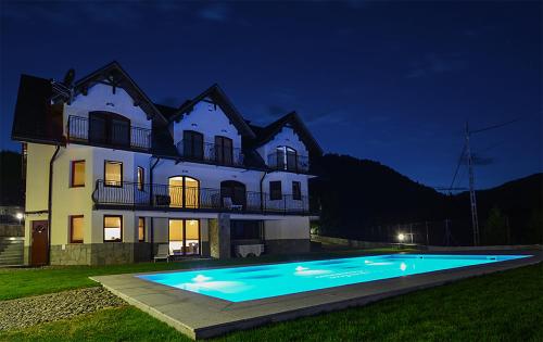 a house with a swimming pool in front of it at night at Willa Nad Wodospadem in Szczawnica
