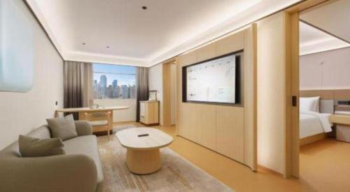 a living room with a couch and a tv at Dalian Liangyun Hotel in Dalian