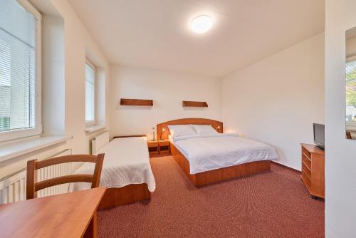 a bedroom with two beds and a desk and a television at Garnet Penzion in Olomouc