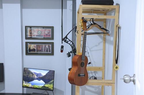 eine Gitarre, die an einer Wand neben einem Fernseher hängt in der Unterkunft Charming Cozy Stay In Heart Of St Albans in St Albans