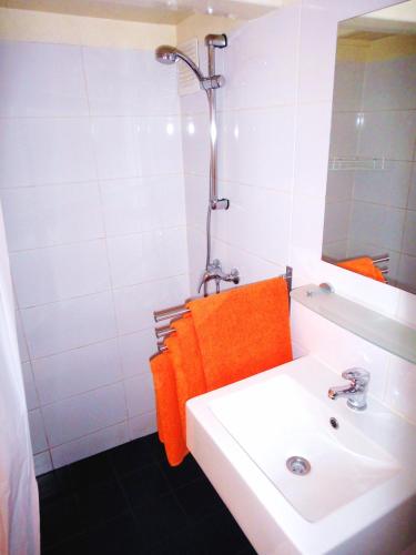 une salle de bains avec un lavabo blanc et une serviette orange dans l'établissement Orange Suite Studio, à Amsterdam