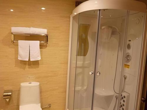 a bathroom with a shower and a toilet and towels at GreenTree Inn Zibo Renmin Park in Zibo
