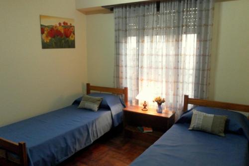 2 camas individuais num quarto com uma janela em Amapolas Huéspedes em Tandil