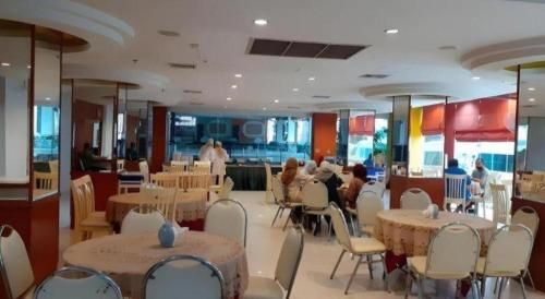 ein Restaurant mit Tischen, weißen Stühlen und Menschen darin in der Unterkunft Pratunam Hotel in Ban Si Than