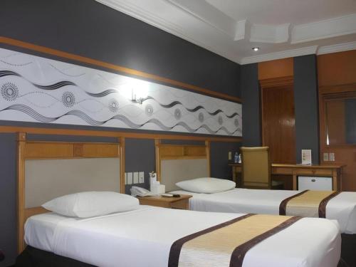 ein Hotelzimmer mit zwei Betten mit weißen Laken in der Unterkunft Hotel Yasmin in Jayapura