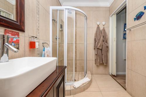um banheiro com chuveiro e pia branca em Keiskama B & B em Port Elizabeth