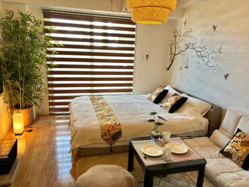 a bedroom with a bed and a couch and a table at ミミハウス幕張 in Chiba