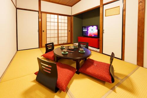 a living room with a table and chairs and a tv at 畳庵嵐山 in Kyoto
