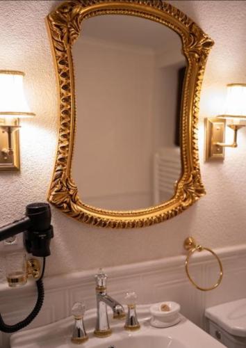 a bathroom with a gold mirror and a sink at John Bull House in Buzău