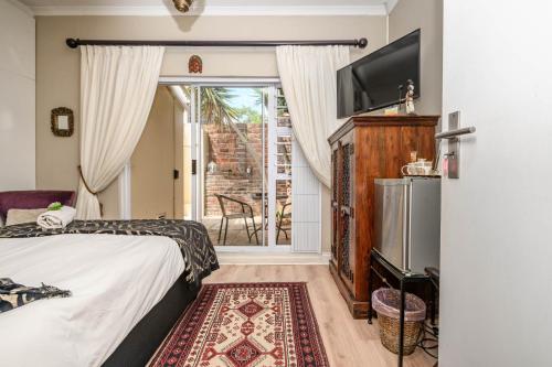 um quarto com uma cama, uma televisão e uma varanda em Keiskama B & B em Port Elizabeth