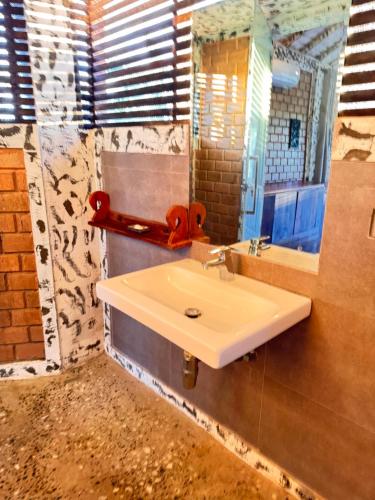 タンガラにあるOHEIの白い洗面台と鏡のあるバスルーム