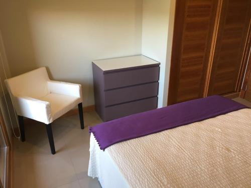a bedroom with a bed and a chair and a dresser at Apartamentos Lanceata I in A Lanzada