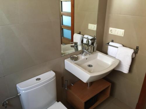 a bathroom with a white toilet and a sink at Apartamentos Lanceata I in A Lanzada
