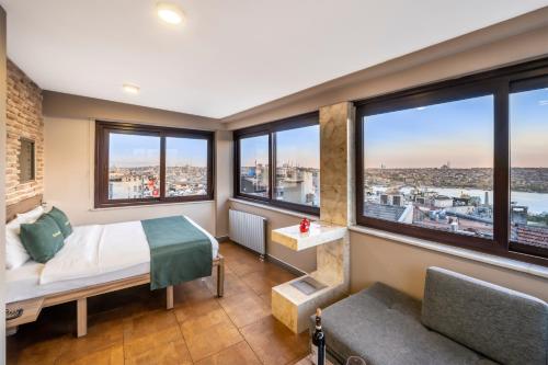 a bedroom with large windows and a bed and a couch at The Pera Hotel in Istanbul