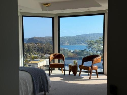 a bedroom with two chairs and a view of the water at Breathtaking views at Vista by the Sea in Copacabana