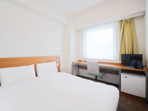 a hotel room with a bed and a desk with a computer at Comfort Inn Nagasaki Airport in Omura
