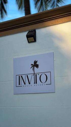 Un letrero para una institución con una palmera. en Invito Beach Resort, en Kannur