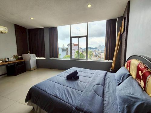 ein Schlafzimmer mit einem blauen Bett und einem großen Fenster in der Unterkunft The Rest Phuket in Phuket