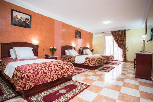 Hôtel Les Ambassadeurs في مراكش: غرفة فندقية بسريرين وجدران برتقالية