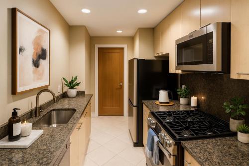 a kitchen with a stove and a sink and a microwave at Luxury 2-Bedroom Apartment in Coal Harbour with Stunning City Views in Vancouver