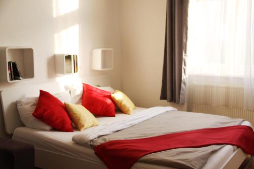 Schlafzimmer mit einem Bett mit roten und gelben Kissen in der Unterkunft Apartment Inzersdorferstraße in Wien
