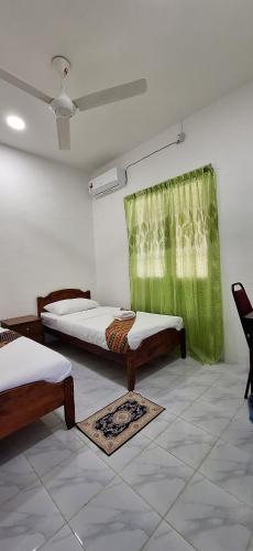 a room with two beds and a green curtain at Sofea Rania Homestay in Kota Belud