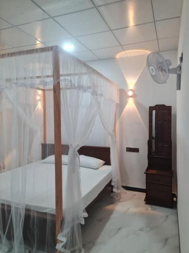 a bedroom with a canopy bed with white curtains at Frida Cove in Weligama