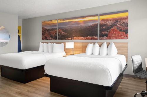 a hotel room with two beds and a painting on the wall at Days Inn by Wyndham Las Vegas in Las Vegas