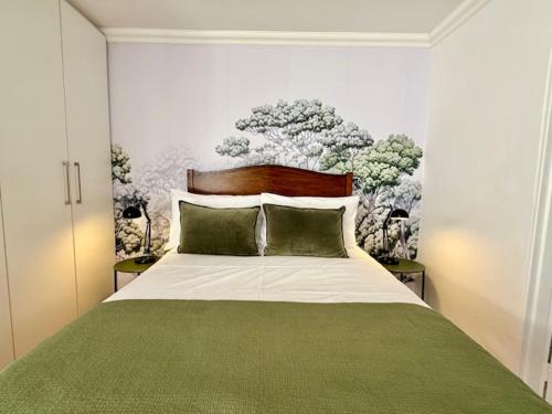 een slaapkamer met een groot bed en een groene deken bij The Sultan Cottage in Stellenbosch