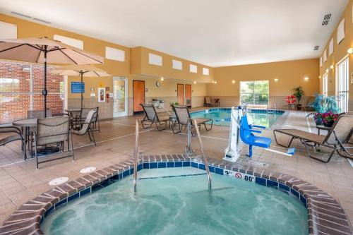 a pool with chairs and a table and a swimming pool at Comfort Suites Urbana Champaign, University Area in Champaign