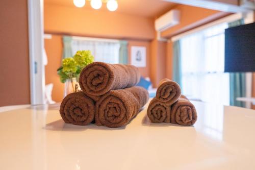 綺麗に改装されたアパートメント 京都や新大阪駅へアクセス良好 3ベッド 1バスルーム في أوساكا: كومة من المناشف البنية موضوعة على طاولة