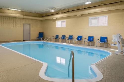 a large swimming pool with blue chairs around it at AmericInn by Wyndham Urbana Champaign University Area in Champaign