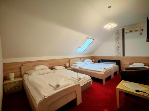 two beds in a room with a red carpet at Menta Rooms & Bar in Kapuvár