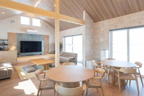 a living room with tables and chairs and a tv at HIGASHIKAWA Villa 瑞月 in Higashikawa