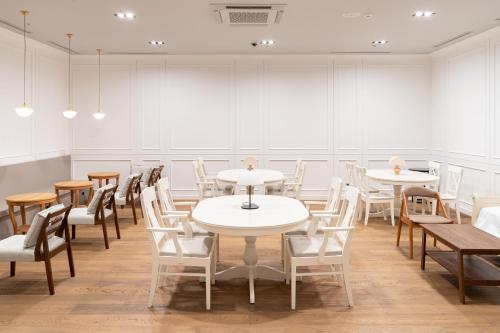 Una habitación con mesas y sillas blancas y ventanas. en Celib Yeoui, en Seúl