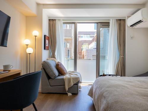 a bedroom with a bed and a chair and a window at RARE-EBISU BREEZE Apartment in Tokyo