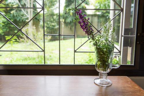 a vase of flowers sitting on a table in front of a window at Phuttal Residence in Phra Nakhon Si Ayutthaya
