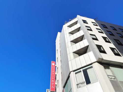a tall white building with a blue sky in the background at Pioland Hotel in Saitama