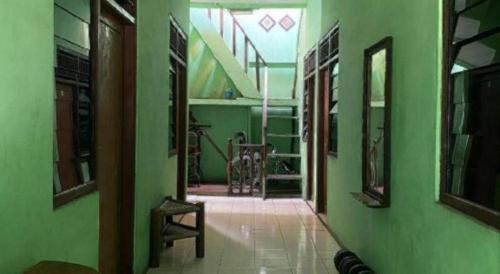 a hallway with green walls and a chair in a room at Hotel O Kost Bunda Syariah in Pekayon Satu