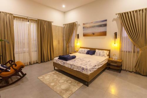 een slaapkamer met een bed, een stoel en ramen bij The Coastal Pearl in Karachi