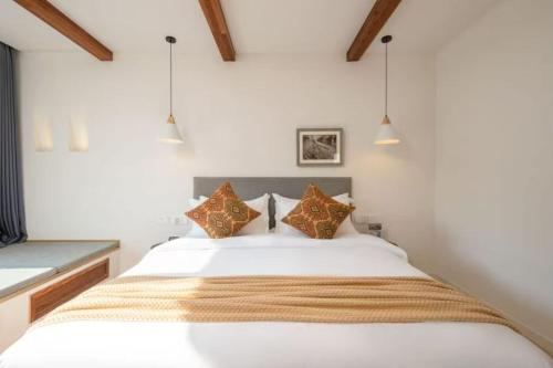 ein Schlafzimmer mit einem großen weißen Bett und Kissen in der Unterkunft Huazhu Luxury Huangshan Warm Wood Homestay Tangkou Nandamen Branch in Tangkou