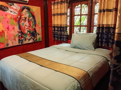 a bedroom with a bed with a painting on the wall at ouychai resort home stay in Chiang Mai
