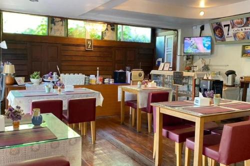 ein Restaurant mit Tischen und Stühlen in einem Raum in der Unterkunft Seven Senses Guesthouse in Chiang Mai