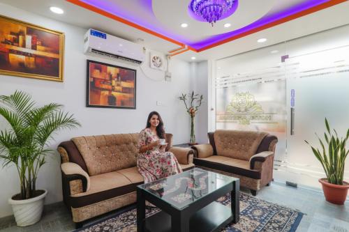 une femme assise sur un canapé dans un salon dans l'établissement Via Ashiyana Inn, à Patna