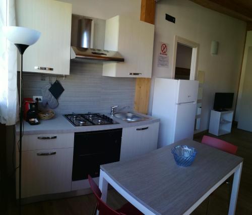 a kitchen with a stove and a sink and a table at Appartamenti Vacanze Mareemare in Capo dʼOrlando