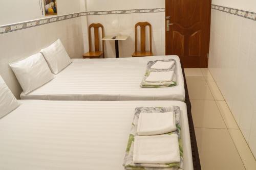 Dos camas en una habitación con sábanas y toallas blancas. en Cường Phú Hotel Hồ Chí Minh, en Ho Chi Minh