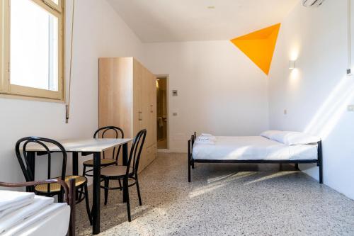 a room with a bed and a table and chairs at Meet Hostel Cervia in Cervia