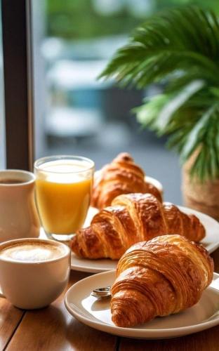 フォッジャにあるboutique teatro b&bのクロワッサン2皿とオレンジジュース付きテーブル