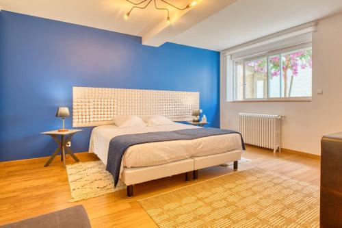 a blue bedroom with a bed and a window at L'envie Eymet in Eymet